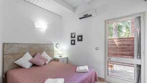 Une chambre à coucher avec un lit, une table de chevet, une lampe et une vue à travers une porte vitrée.