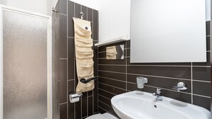 Une salle de bain équipée de toilettes, d’un lavabo, d’un porte-serviettes et d’un miroir.