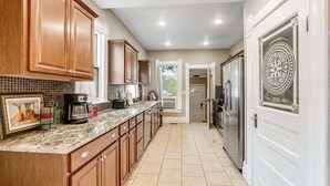 A kitchen with wooden cabinets, a granite countertop, and stainless steel appliances. - 3BR near Downtown COS with fenced Backyard Seating (Colorado Springs)