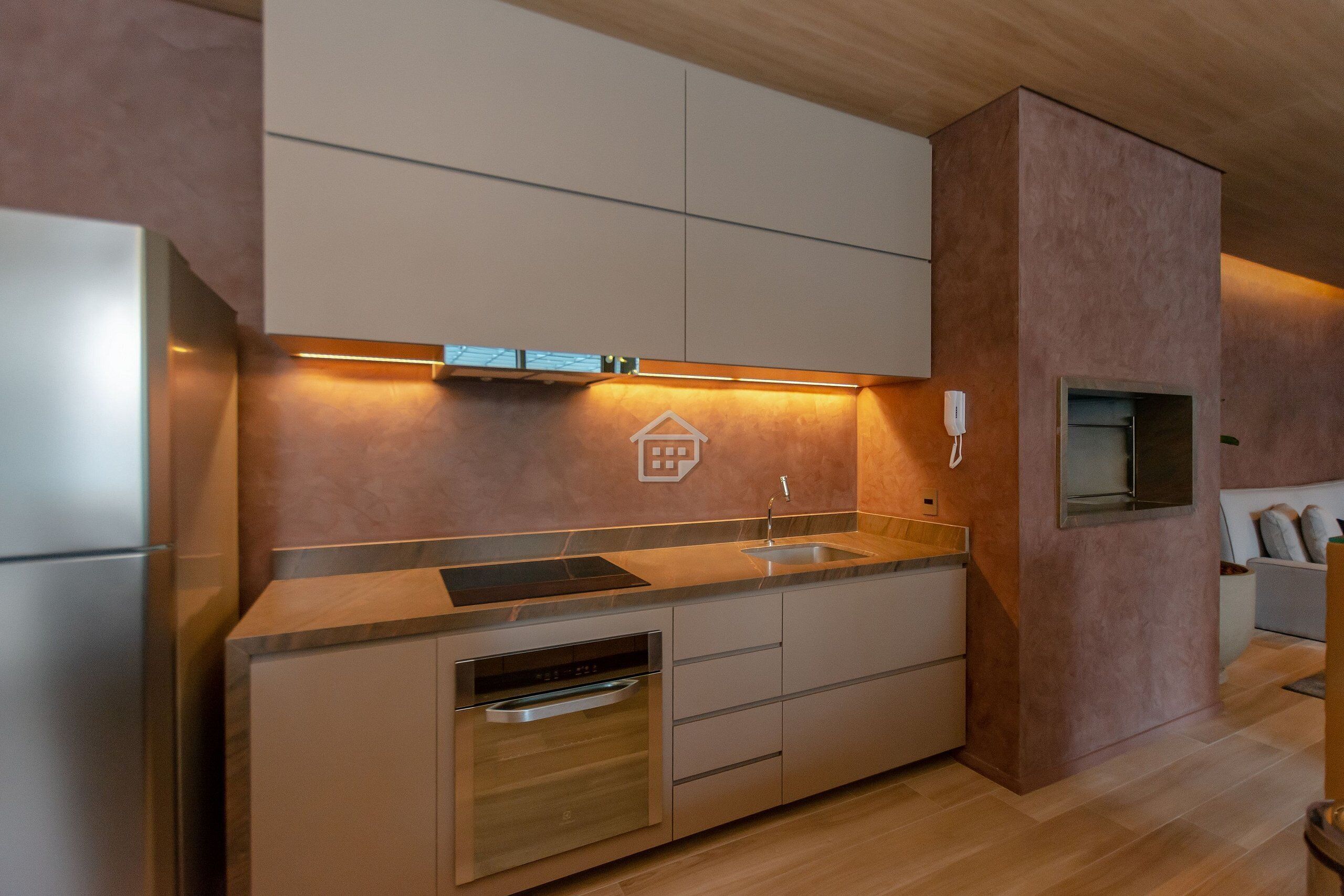 A modern kitchen with built-in appliances, a wooden countertop, and a recessed light.