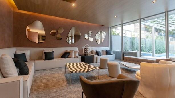 Un salon moderne avec un ensemble de canapés, une table basse à motifs et des miroirs fixés au mur.