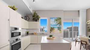 Una cocina moderna con electrodomésticos integrados, una isla central y un comedor con vistas a la ciudad.