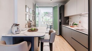 Uma cozinha moderna com área de jantar, uma torradeira, uma cesta e vista através de uma porta aberta.