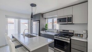 Et moderne køkken med en central ø, rustfrie hvidevarer og udsigt ud