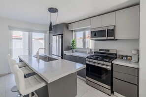 A modern kitchen with a central island, stainless steel appliances, and a view to the outside. - Private Pool Villa Near Palm & Eagle Beach (Noord)