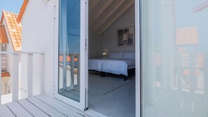 Et soveværelse med en seng, et natbord, en lampe og et vindue.