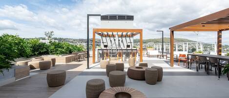 Un espace extérieur aménagé avec des meubles en osier, une pergola et une vue sur la ville.