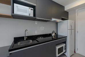 Eine moderne Küche mit schwarzem Arbeitsplatz, Spüle aus Edelstahl, Mikrowelle und eingebautem Ofen.