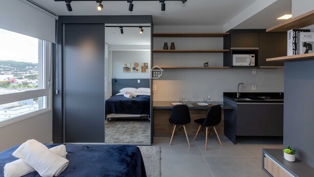 Une chambre d’hôtel moderne équipée d’un lit, d’un bureau, d’un four à micro-ondes et offrant une vue sur la ville.