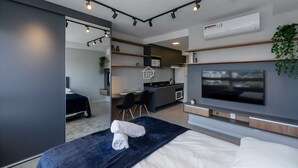 Une chambre d’hôtel moderne équipée d’un lit, d’une télévision, d’un bureau et d’une kitchenette.
