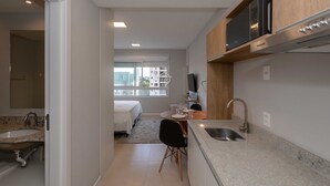 A compact kitchen with a dining area, a built-in microwave, and a window with a city view.