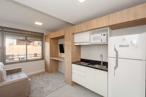Una cocina moderna con gabinetes blancos, un microondas integrado y un refrigerador.