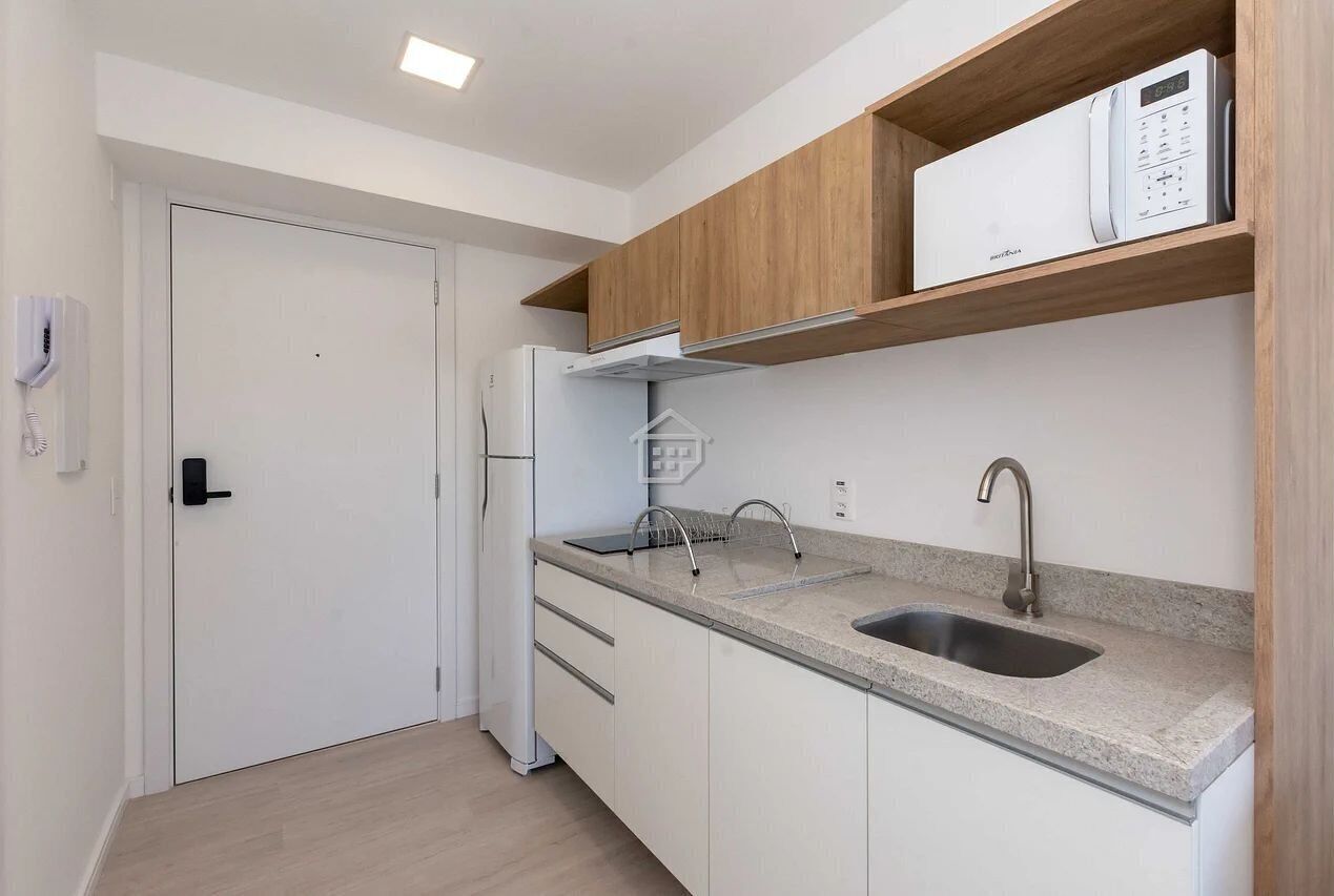 A compact kitchen with a built-in microwave, a stainless steel sink, and wooden upper cabinets.