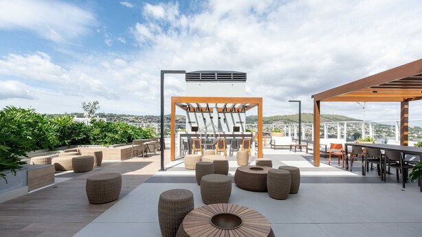 Un espace extérieur aménagé avec des meubles en osier, une pergola et une vue sur la ville.
