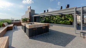 Un bar amb terrassa al teulat, seients, barra i paret coberta de vegetació.