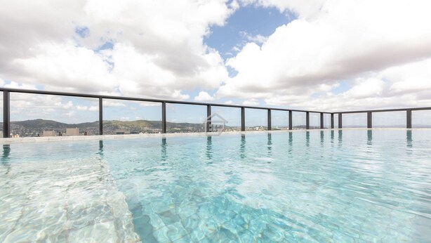 A clear swimming pool with a metal railing, a beach view, and mountains in the background. - Panoramic View in Porto Alegre MJ08H (Porto Alegre)