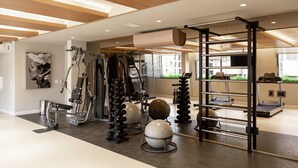 Une salle de sport moderne équipée de matériel d’exercice, d’un miroir et offrant une vue sur l’extérieur.