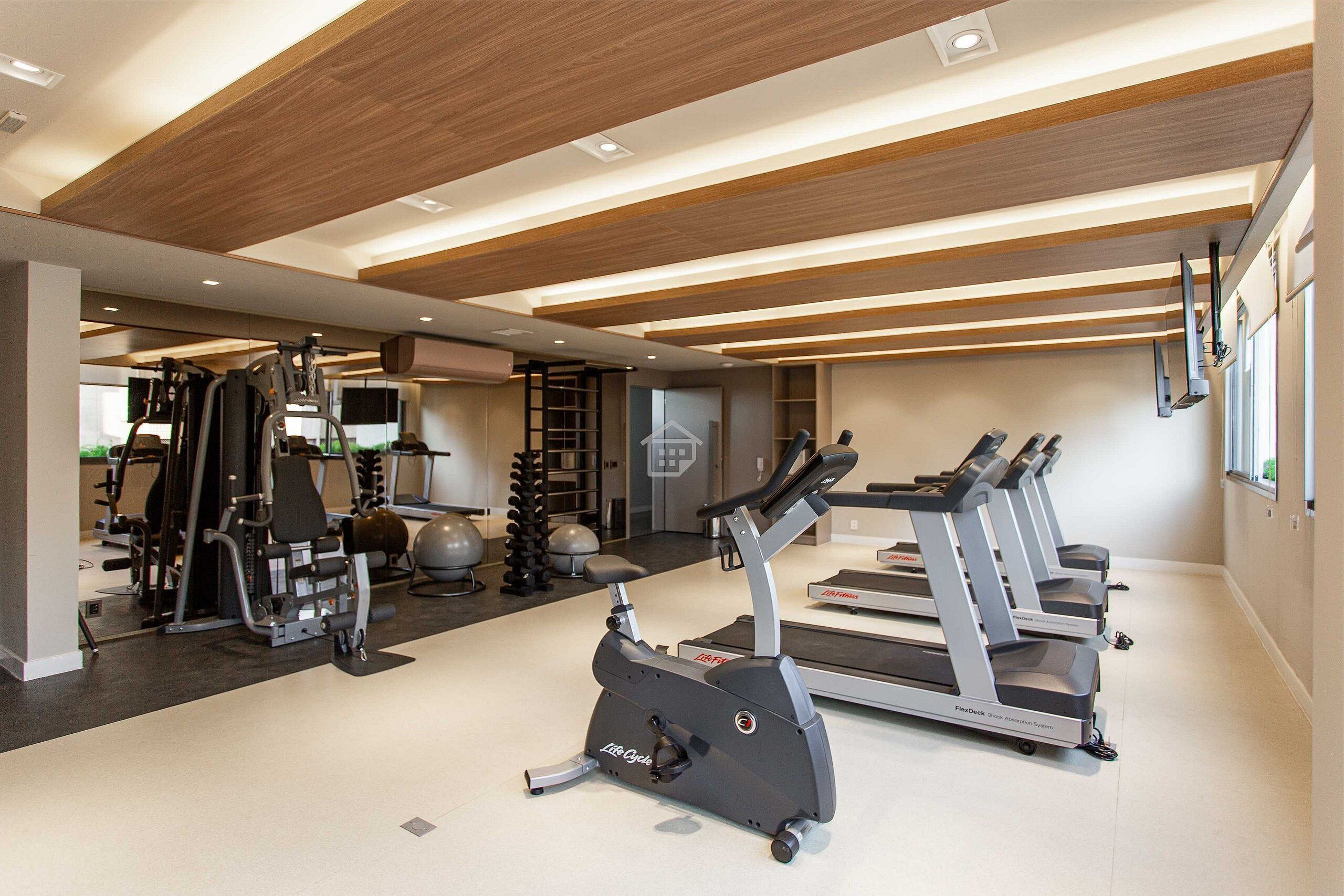 Et fitnesscenter med løbebånd, crosstrainere og styrketræningsudstyr.