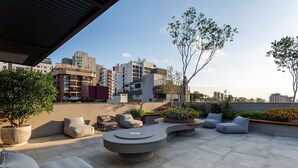 Un espace extérieur aménagé avec des meubles modernes, des plantes en pot et une vue sur le paysage urbain.
