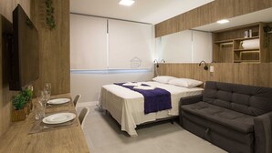 Une chambre à coucher moderne avec un lit, un canapé, une table à manger avec des chaises, un téléviseur et un miroir.