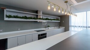 Ett modernt kök med en lång arbetsbänk, en inbyggd ugn och en hängande lampa.
