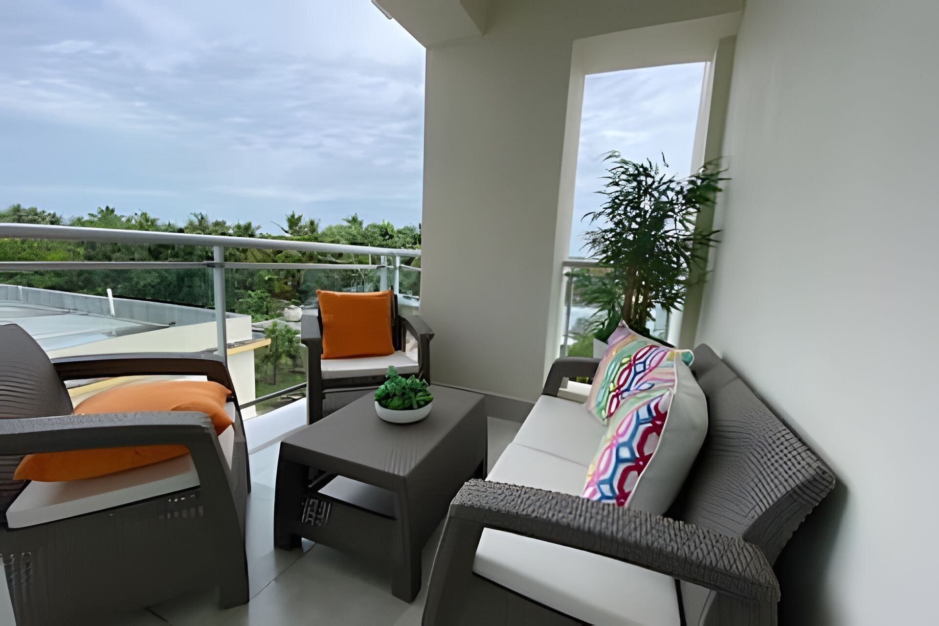 A balcony with a sofa, a small table, and a potted plant.