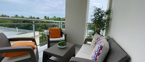 A balcony with a sofa, a small table, and a potted plant.