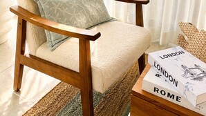 A chair with a cushion, a woven basket, a book titled 'LONDON ROME,' and a potted plant. - Apartamento Delicado Próximo a la Playa (Boca Chica)