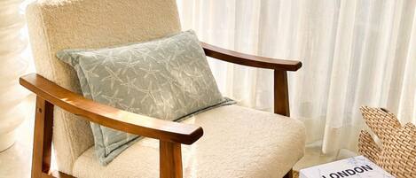 A chair with a cushion, a woven basket, a book titled 'LONDON ROME,' and a potted plant.