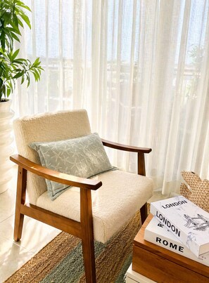 A chair with a cushion, a woven basket, a book titled 'LONDON ROME,' and a potted plant. - Apartamento Delicado Próximo a la Playa (Boca Chica)