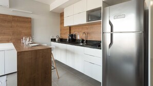 Een moderne keuken met een houten kookeiland, roestvrijstalen apparatuur en witte kasten.