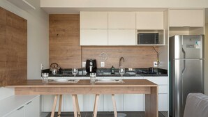 Een moderne keuken met een houten aanrecht, roestvrijstalen apparatuur en een eethoek met een tafel en stoelen.