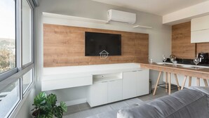Een moderne keuken met een ingebouwde magnetron, een houten aanrecht en een raam met uitzicht op een stadsbeeld.