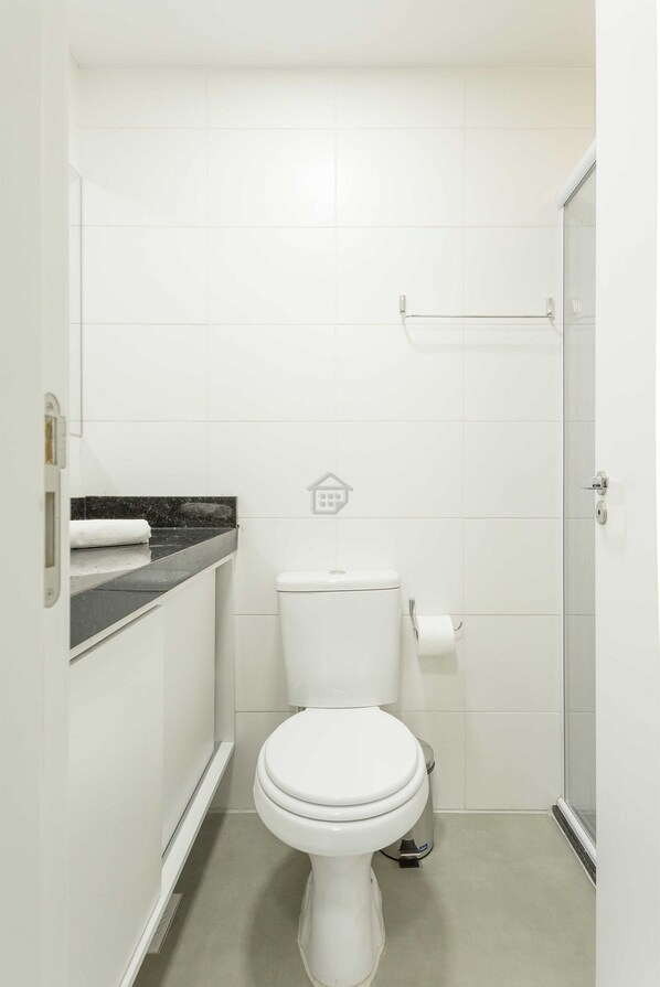 A small, modern bathroom with a toilet, a shower, and a sink.