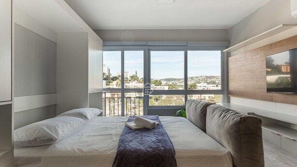 Una camera da letto moderna con un'ampia finestra, un letto, un divano e una TV a schermo piatto.