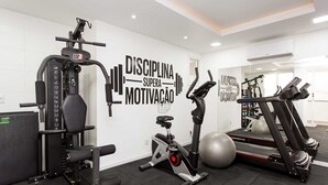 Una palestra con attrezzature per esercizi, testo motivazionale sulla parete e uno specchio a parete.