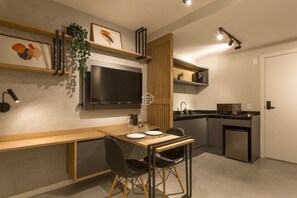 Cozinha moderna com área de refeições, eletrodomésticos embutidos e TV de tela plana.