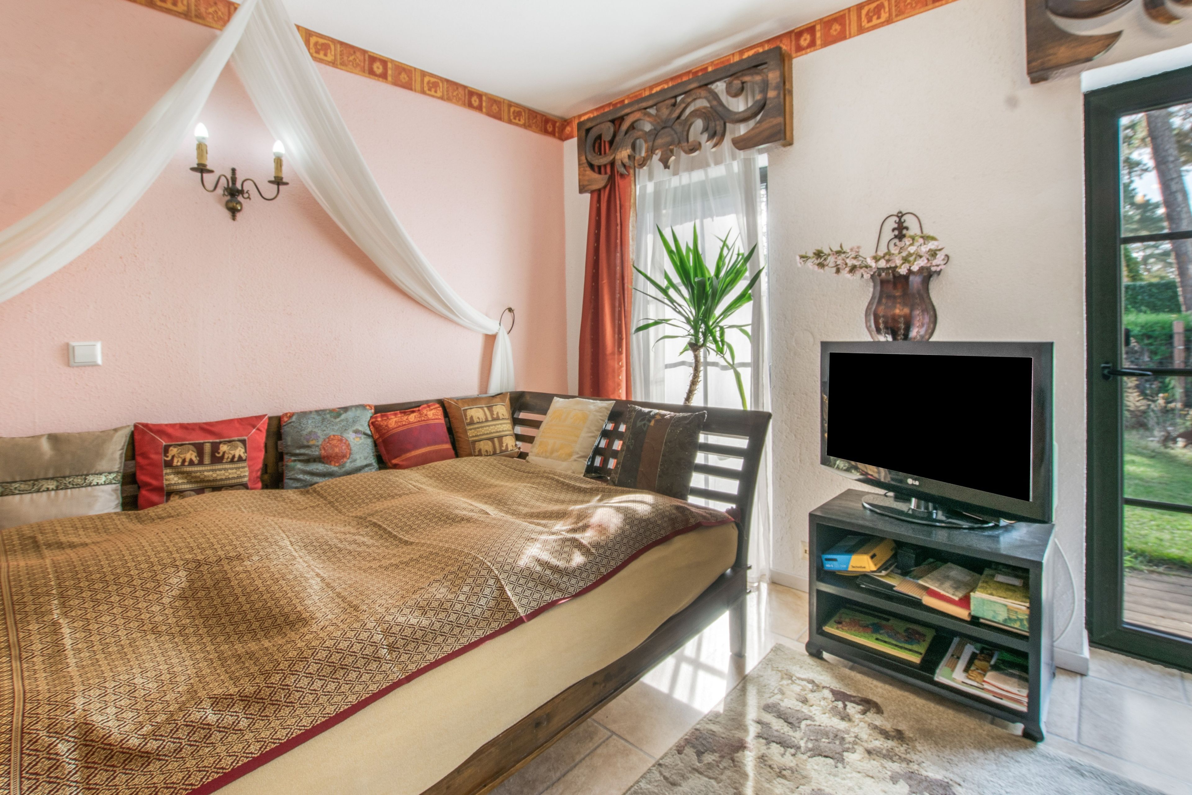 A bedroom with a bed, a television, and a window with curtains.