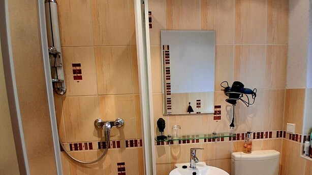 Ein Badezimmer mit Duschkabine aus Glas, einem Waschbecken mit Spiegel darüber und einer Toilette.