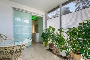 A room with a glass table, potted plants, and a sliding door leading to another space. - Apartment "La Vida" for 3 Guests, 60 m² with Shared Garden, Wi-Fi and Air Conditioning (Hoppegarten)