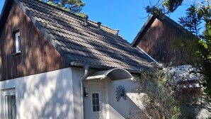 A two-story house with a tiled roof, a front door, and a small garden area. - Apartment "La Vida" for 3 Guests, 60 m² with Shared Garden, Wi-Fi and Air Conditioning (Hoppegarten)