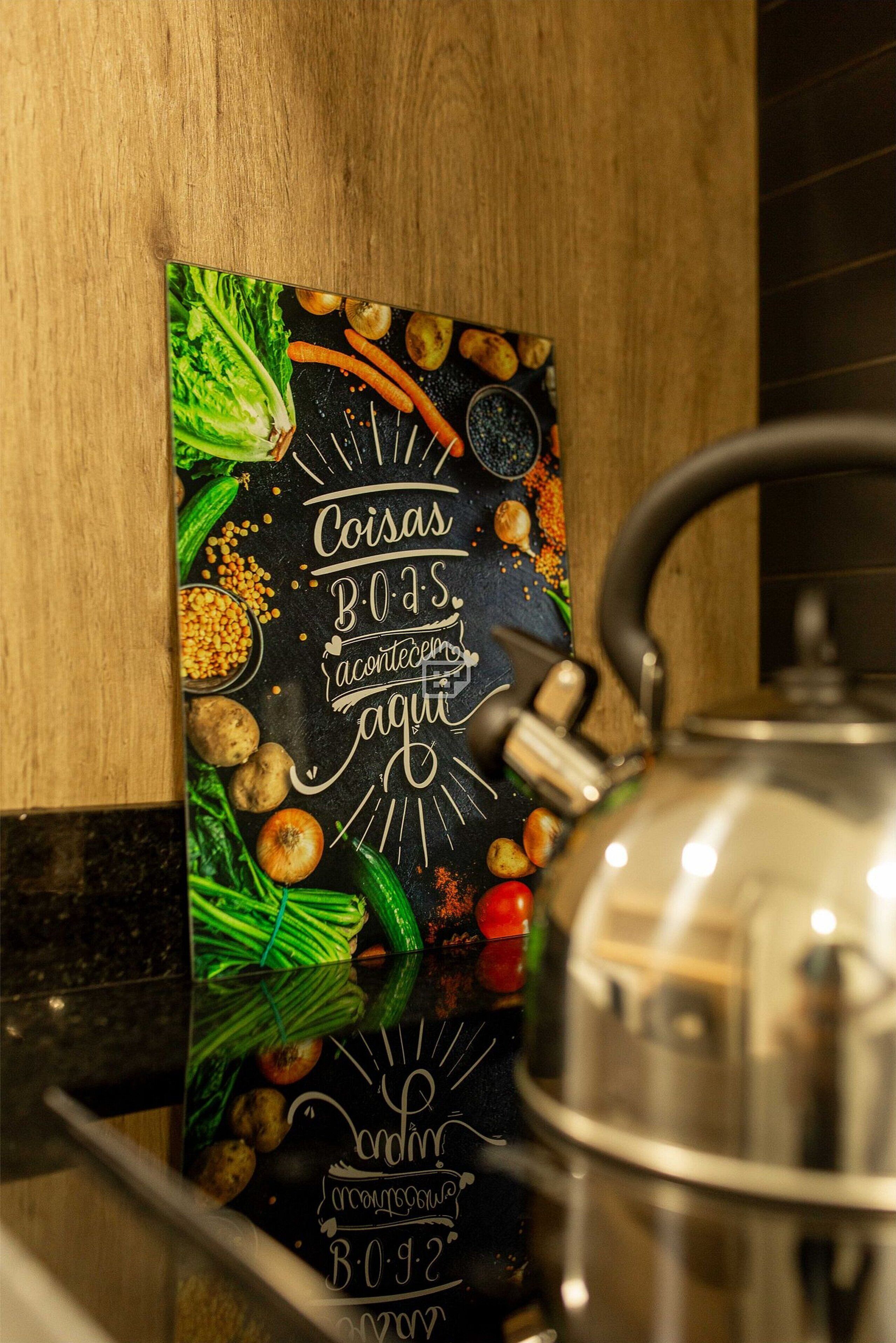 A kitchen counter with a kettle, a chalkboard menu featuring vegetables, and a wooden wall.