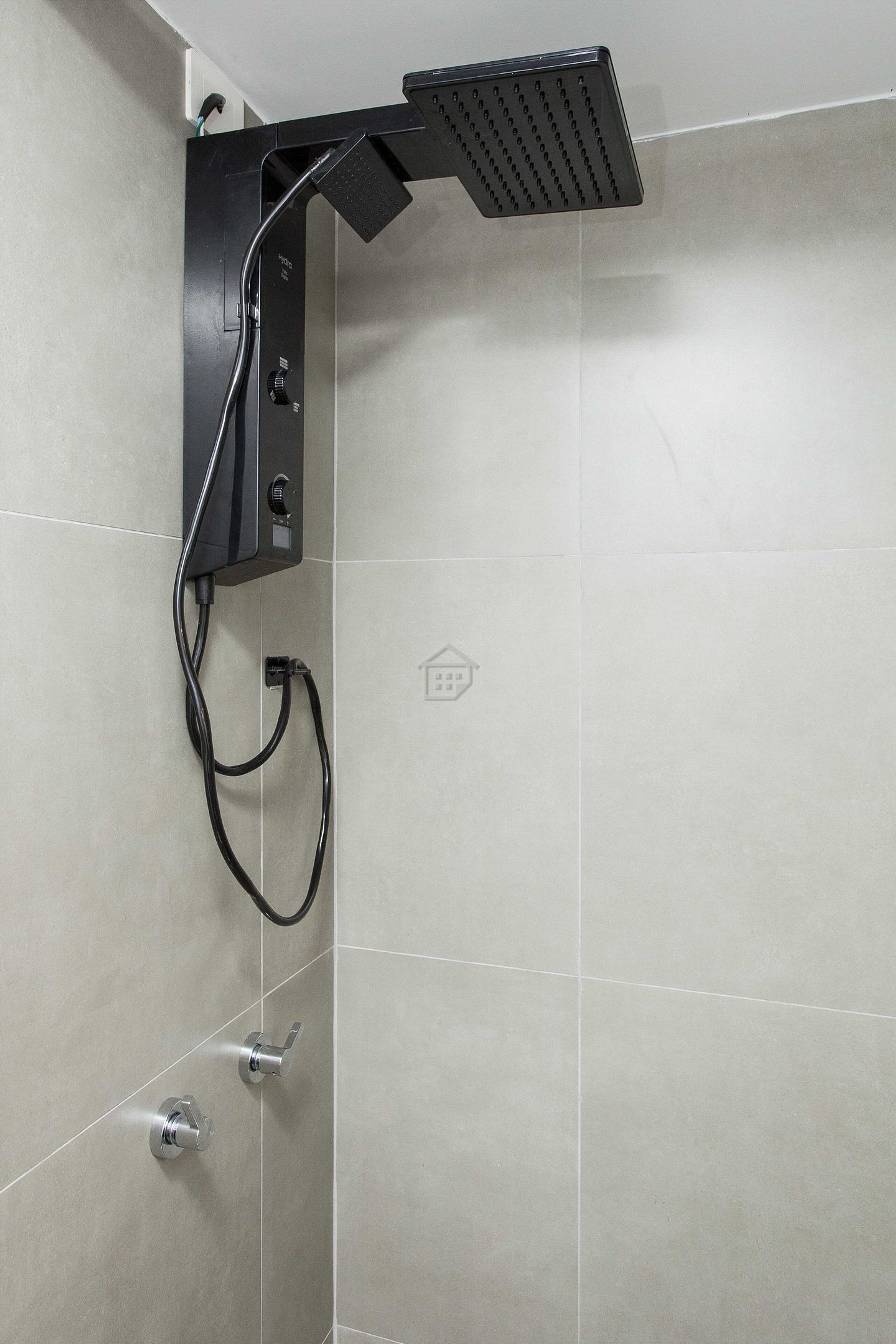 A shower with a handheld showerhead, a wall-mounted control panel, and a flexible hose.