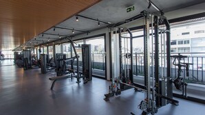 A gym with various exercise machines, large windows, and a wooden ceiling. - Studio moderno: rooftop no coração do Rio Branco (Porto Alegre)