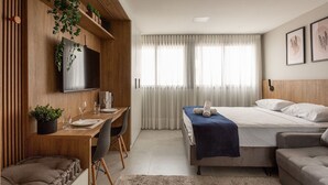 A modern bedroom with a bed, a desk, and a TV. - Studio sofisticado e moderno no bairro Rio Branco (Porto Alegre)