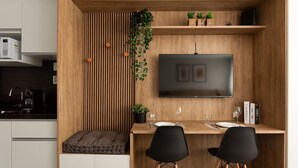 A modern kitchen with a built-in microwave, a coffee machine, and a wooden wall paneling. - Studio sofisticado e moderno no bairro Rio Branco (Porto Alegre)