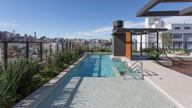A rooftop pool with a city view, surrounded by greenery and modern architecture. - Studio sofisticado e moderno no bairro Rio Branco (Porto Alegre)
