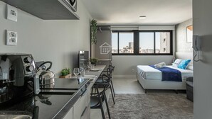 Um apartamento moderno com cozinha compacta, sala de jantar, cama com vista e uma grande janela.