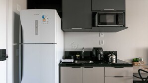 Uma cozinha com geladeira branca, micro-ondas, pia e chaleira.