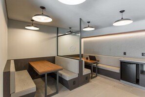 Spazio pubblico moderno e luminoso, con sedute, un bancone e un frigorifero.